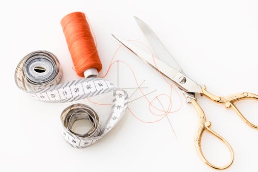 pexels-photo-461035-461035 Photo of sewing essentials: scissors, thread, needles, and tape measure on a white background.